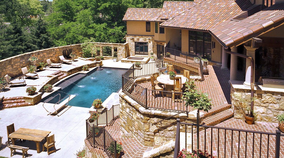Looking down on the exterior pool and lounge area of a Tuscan-style home in Mission Hills, Kansas. Architecture and landscape architecture by NSPJ Architects.