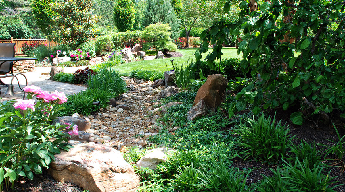 Dry creek bed made from rock mix at Prairie Village, Kansas home. Landscape architecture by NSPJ Architects.