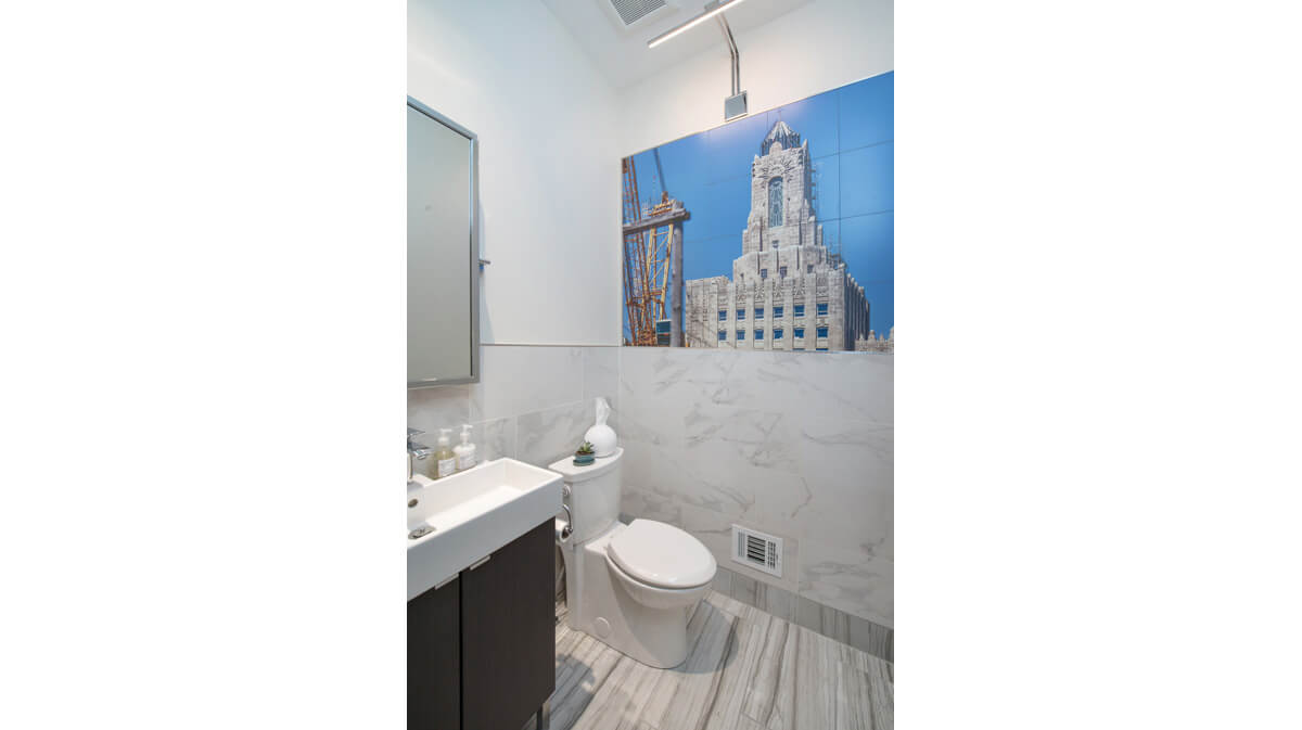 Photograph of guest bath in a modern home in Kansas City, Missouri. Features include marble floors and wainscoting and original artwork. Architecture, landscape architecture and interior design by NSPJ Architects.