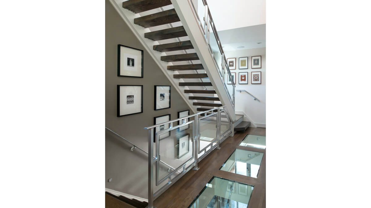 Interior stair tower in a modern urban home in Kansas City, Missouri. The two stair flights are separated by a hall that includes a glass panels in the floor to draw natural sunlight through the entire house. Architecture, landscape architecture and interior design by NSPJ Architects.
