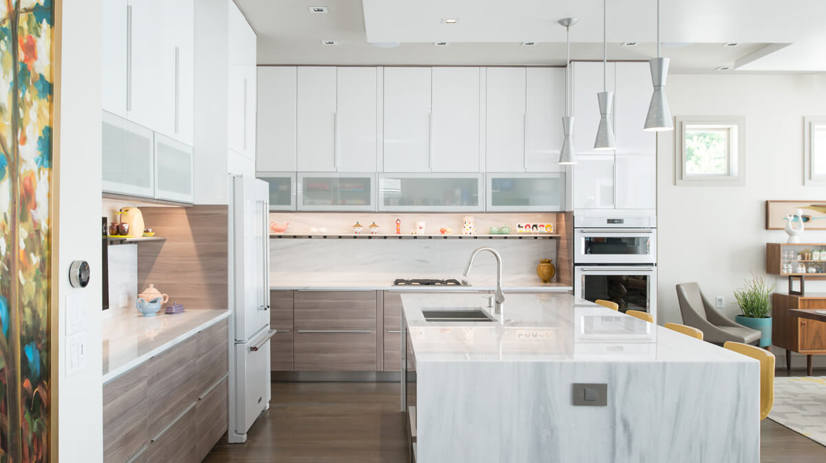 Modern kitchen in Kansas City Missouri (side view). The kitchen features white Ikea cabinets, marble countertops and island, and light wood floors. Architecture, landscape architecture and interior design by NSPJ Architects.