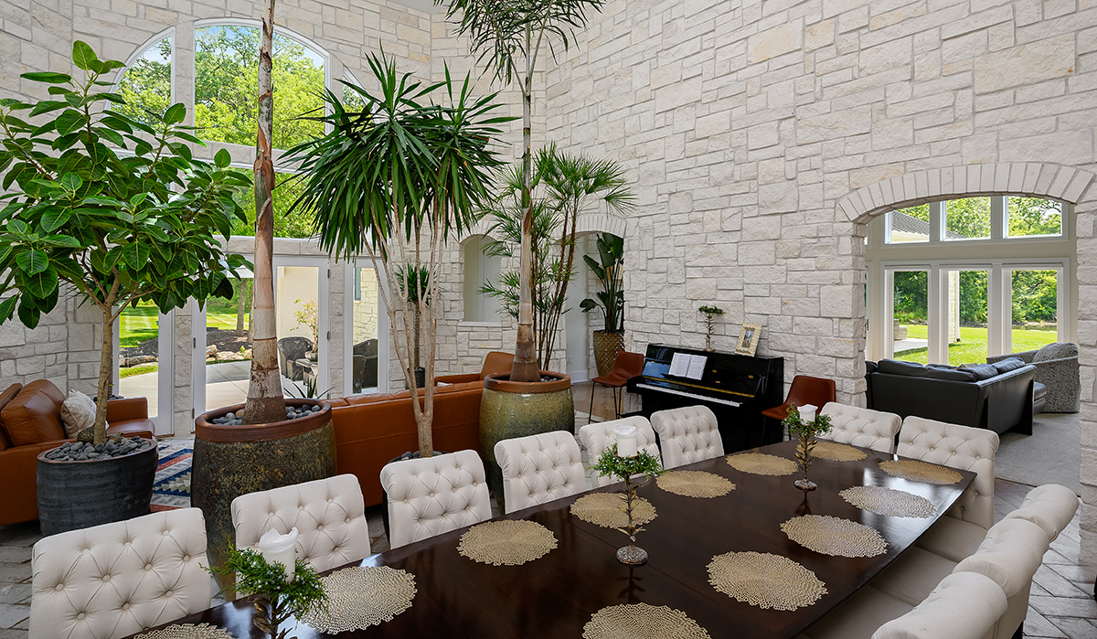 Modern Mediterranean Stone wall, large windows, arched window, dining table, indoor trees