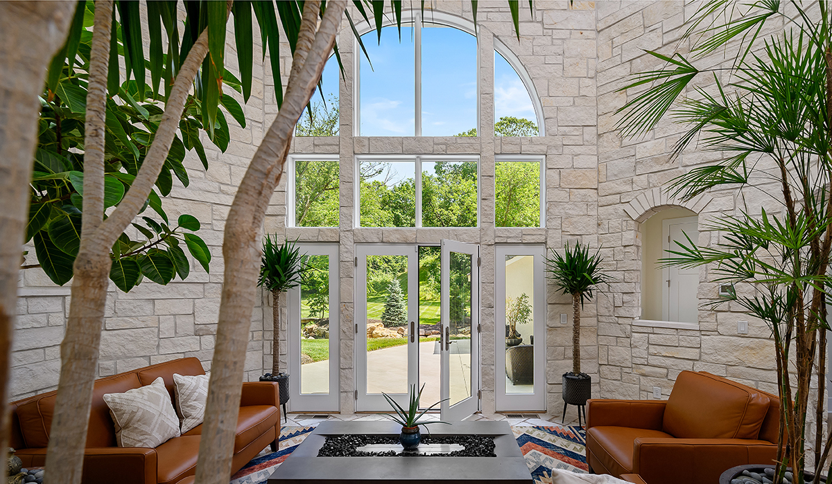 Modern Mediterranean Stone wall, large windows, arched window, couch seating, indoor trees